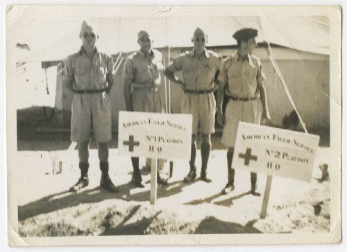 Four men standing behind signs for the AFS 1 Platoon and 2 Platoon Headquarters